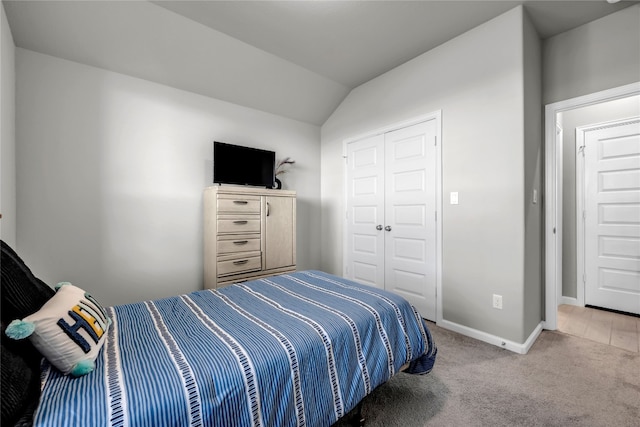 bedroom with a closet, light colored carpet, and lofted ceiling