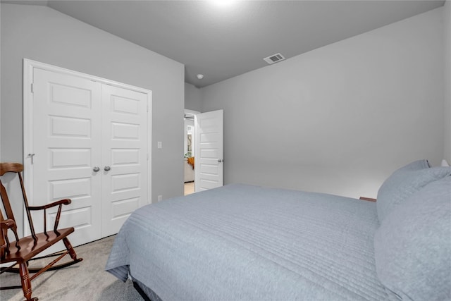 bedroom with light colored carpet, vaulted ceiling, and a closet