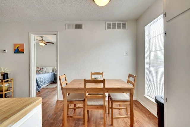 dining room with hardwood / wood-style flooring, ceiling fan, and a textured ceiling