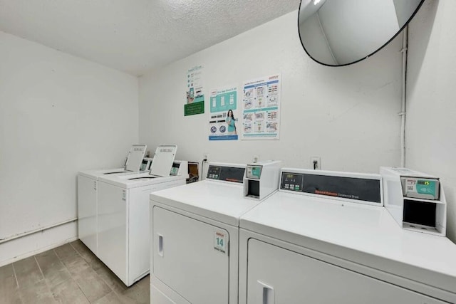 clothes washing area featuring washer and dryer, a textured ceiling, and light hardwood / wood-style floors