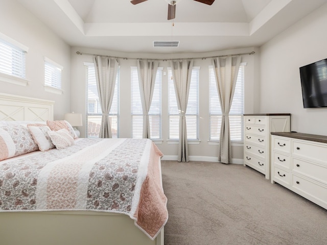 bedroom featuring ceiling fan, light colored carpet, and a raised ceiling