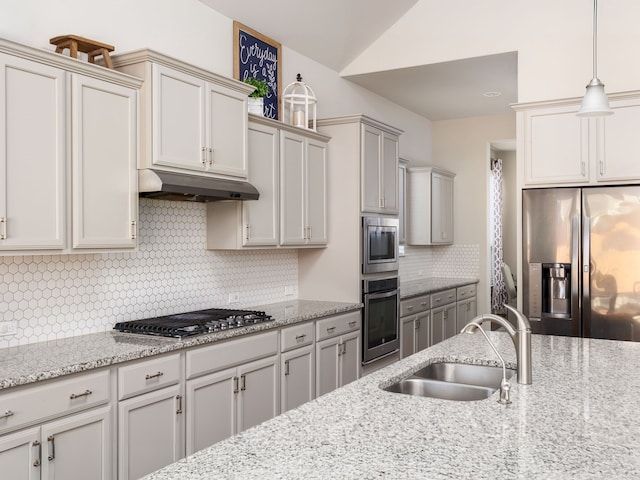 kitchen with decorative light fixtures, sink, appliances with stainless steel finishes, and light stone countertops