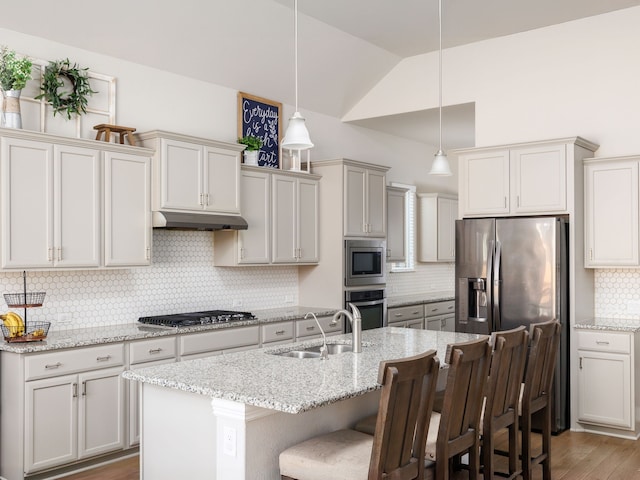 kitchen featuring an island with sink, stainless steel appliances, a kitchen breakfast bar, pendant lighting, and sink