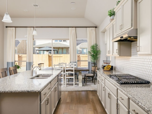 kitchen with tasteful backsplash, dark hardwood / wood-style floors, pendant lighting, sink, and an island with sink