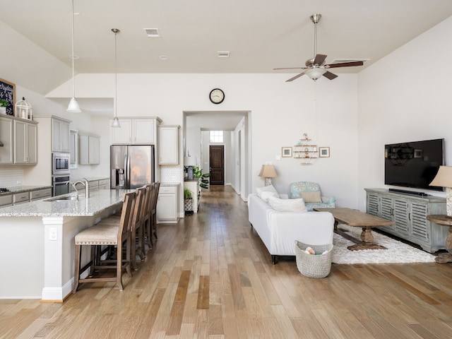 kitchen with decorative light fixtures, backsplash, appliances with stainless steel finishes, and a breakfast bar area