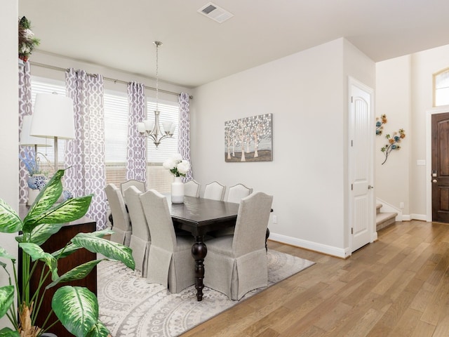 dining area with light hardwood / wood-style flooring and an inviting chandelier