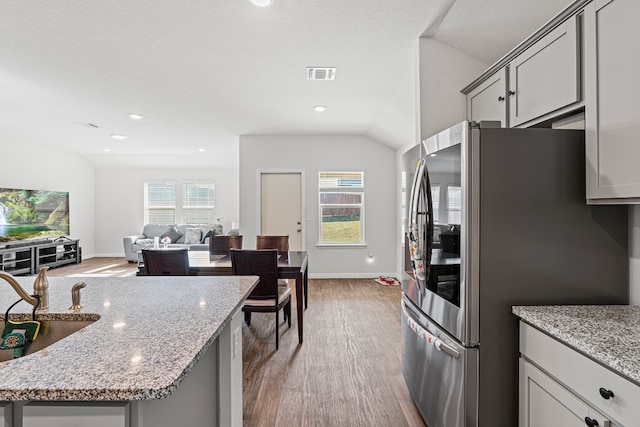 kitchen with hardwood / wood-style flooring, gray cabinetry, stainless steel refrigerator with ice dispenser, and vaulted ceiling