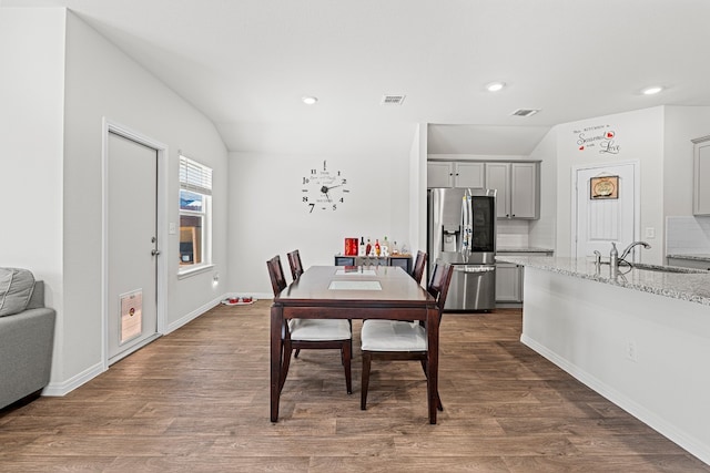 dining space with vaulted ceiling, sink, and dark wood-type flooring