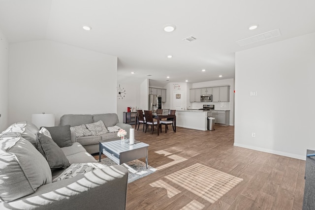 living room with light wood-type flooring and vaulted ceiling