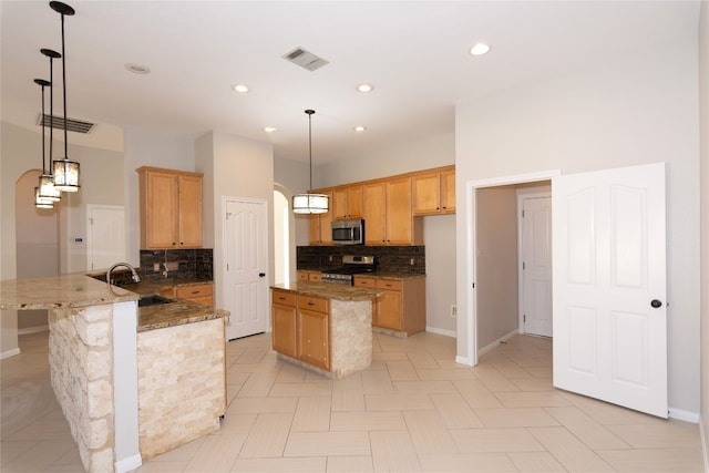 kitchen featuring decorative backsplash, appliances with stainless steel finishes, hanging light fixtures, and sink