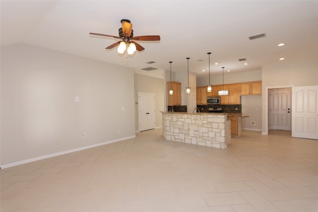 kitchen featuring pendant lighting, ceiling fan, appliances with stainless steel finishes, tasteful backsplash, and a kitchen island