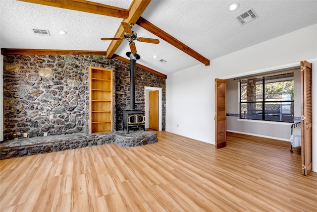 unfurnished living room featuring hardwood / wood-style flooring, ceiling fan, a wood stove, and a textured ceiling