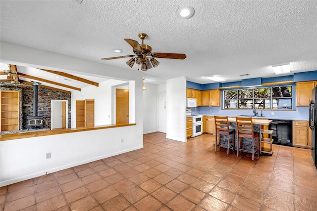 kitchen with a wood stove, vaulted ceiling with beams, a textured ceiling, white appliances, and a kitchen bar