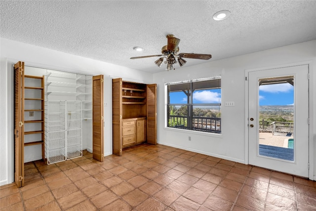 unfurnished bedroom with access to outside, multiple closets, ceiling fan, and a textured ceiling