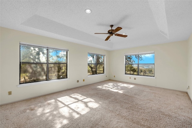 carpeted spare room featuring a tray ceiling, ceiling fan, and a textured ceiling