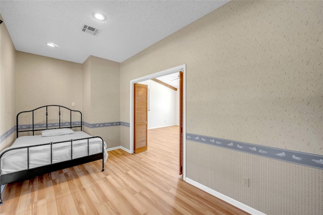 bedroom featuring a textured ceiling and light hardwood / wood-style flooring