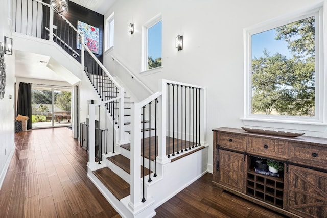 stairway with a towering ceiling and hardwood / wood-style floors