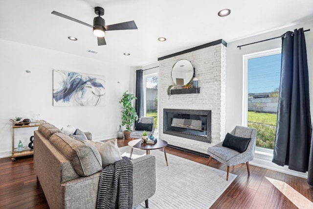 living room with a fireplace, dark hardwood / wood-style floors, plenty of natural light, and ceiling fan