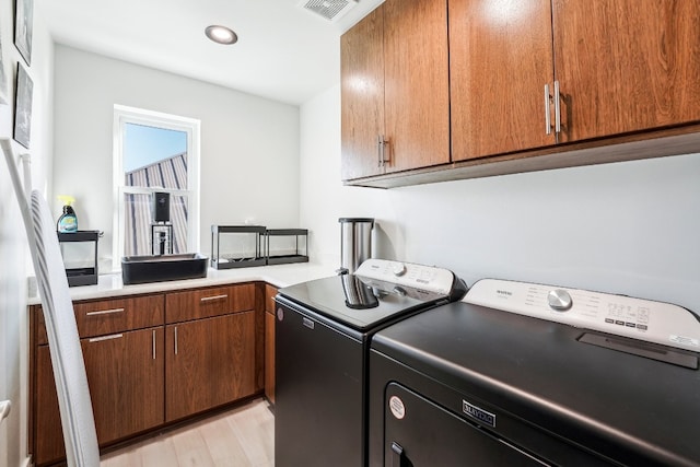 laundry room featuring cabinets, independent washer and dryer, and light hardwood / wood-style flooring