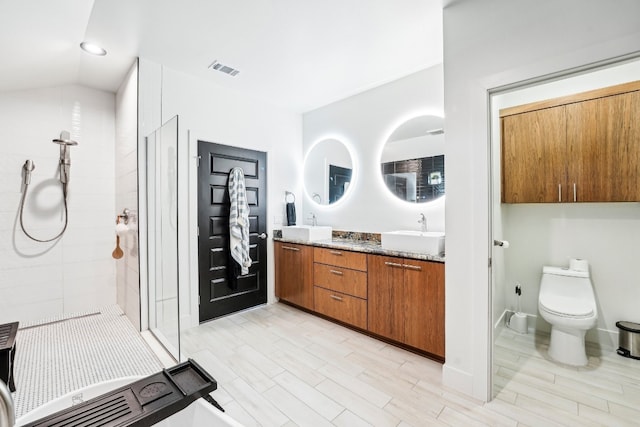 bathroom featuring a tile shower, vanity, lofted ceiling, and toilet