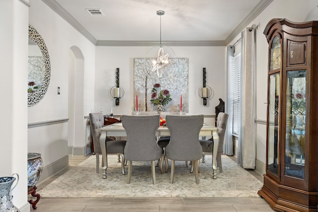 dining space featuring crown molding, light wood-type flooring, and an inviting chandelier