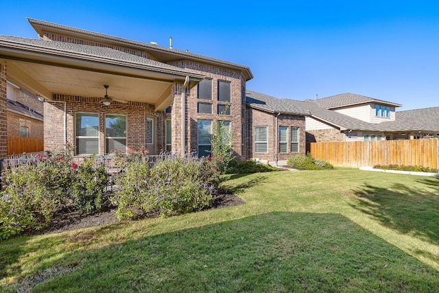 rear view of house featuring a lawn and ceiling fan