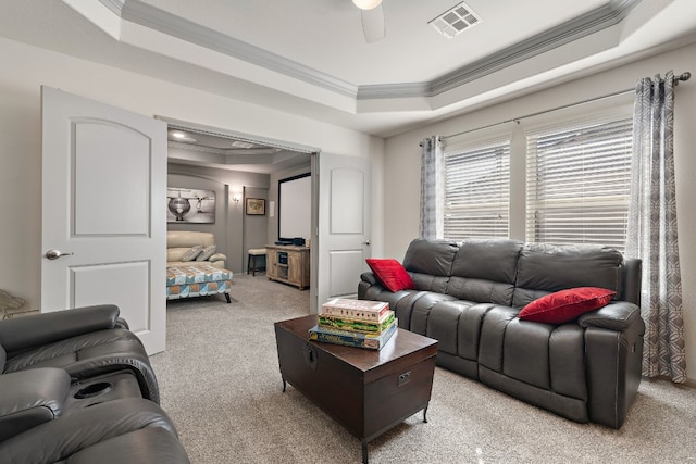 carpeted living room featuring a tray ceiling, ceiling fan, and ornamental molding