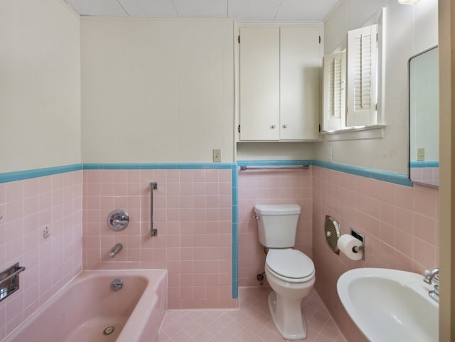 bathroom featuring tile patterned flooring, a bathtub, toilet, and tile walls