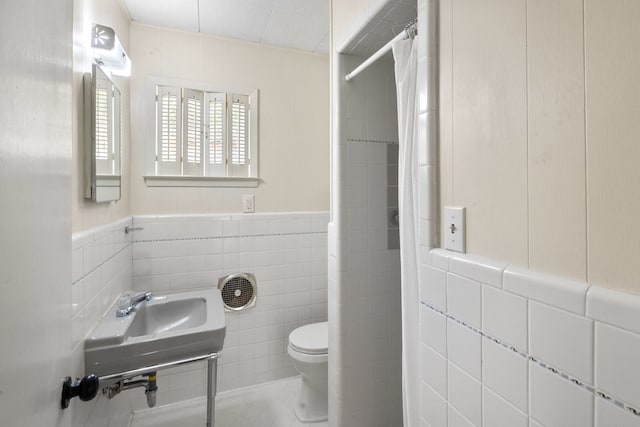 bathroom featuring tile patterned flooring, curtained shower, toilet, and tile walls