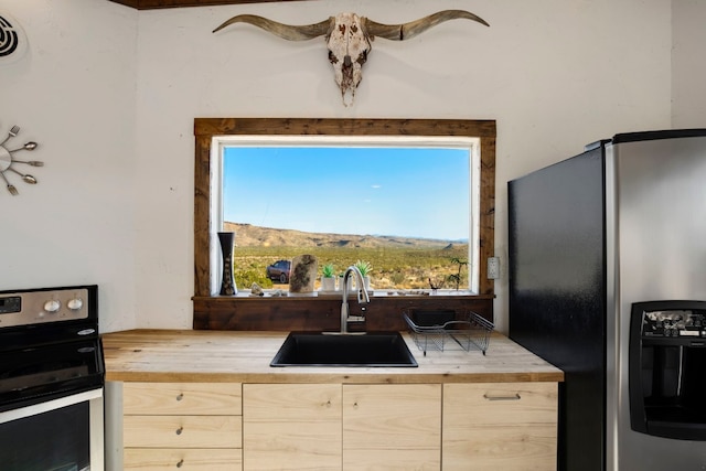 kitchen featuring wood counters, appliances with stainless steel finishes, sink, light brown cabinets, and a mountain view