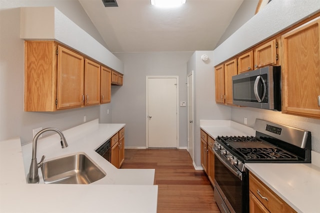 kitchen with appliances with stainless steel finishes, light hardwood / wood-style floors, lofted ceiling, and sink