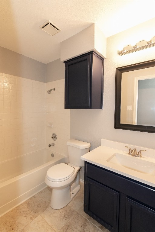 full bathroom with vanity, tile patterned floors, tiled shower / bath, toilet, and a textured ceiling