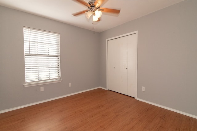 unfurnished bedroom with hardwood / wood-style floors, ceiling fan, a closet, and multiple windows