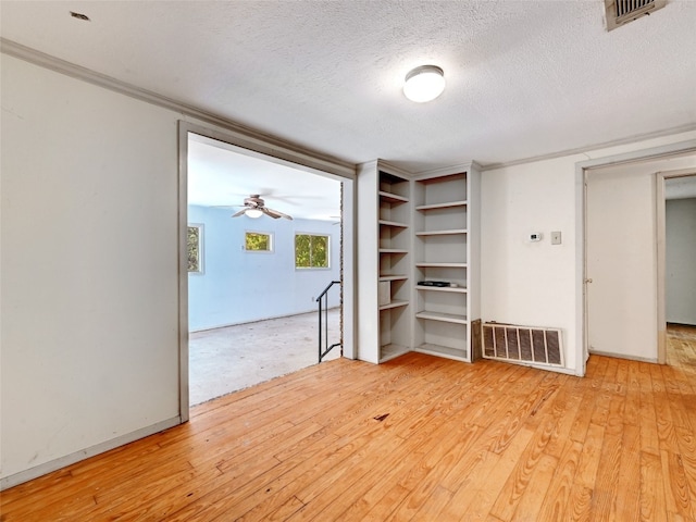 interior space featuring ceiling fan, ornamental molding, a textured ceiling, and light hardwood / wood-style flooring