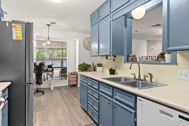 kitchen with light wood-type flooring, white dishwasher, sink, blue cabinetry, and stainless steel refrigerator