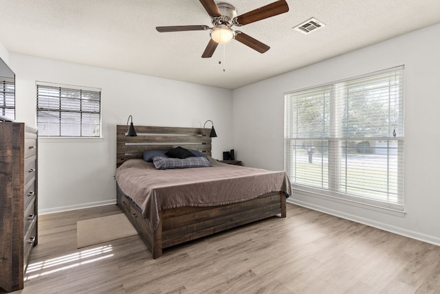 bedroom with ceiling fan, light hardwood / wood-style floors, and a textured ceiling