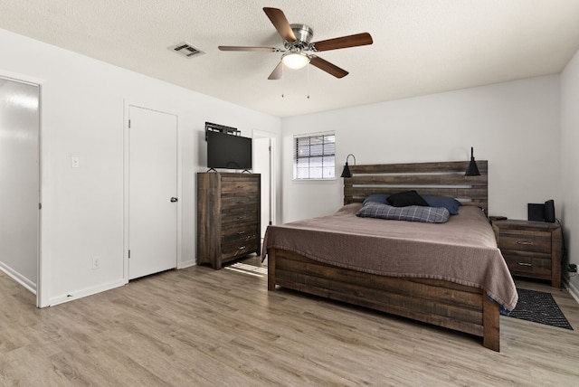 bedroom featuring ceiling fan, light wood-type flooring, and a textured ceiling