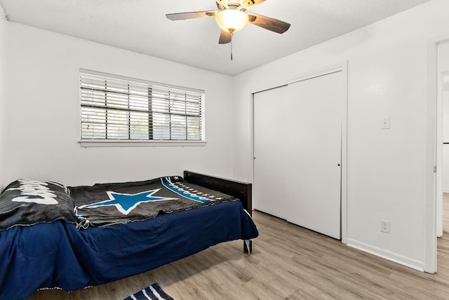 bedroom with ceiling fan, light wood-type flooring, a textured ceiling, and a closet