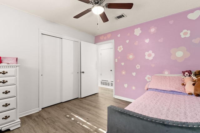 bedroom featuring a textured ceiling, a closet, light hardwood / wood-style floors, and ceiling fan