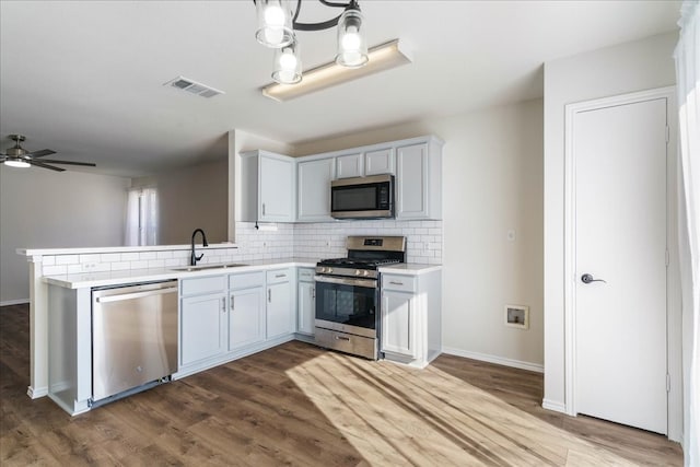 kitchen featuring sink, dark wood-type flooring, white cabinets, ceiling fan with notable chandelier, and appliances with stainless steel finishes