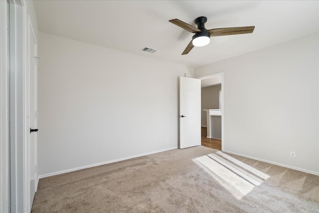 unfurnished bedroom with a walk in closet, light colored carpet, and ceiling fan