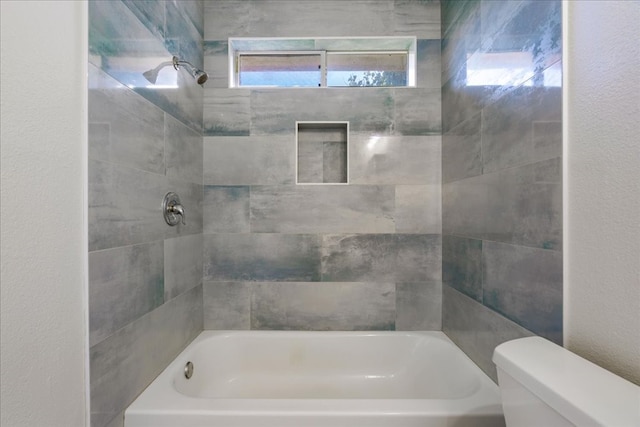 bathroom featuring tiled shower / bath combo and toilet