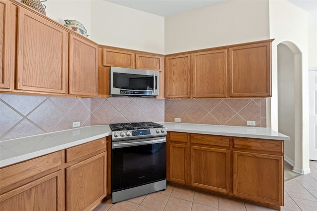 kitchen with light tile patterned floors, backsplash, and appliances with stainless steel finishes