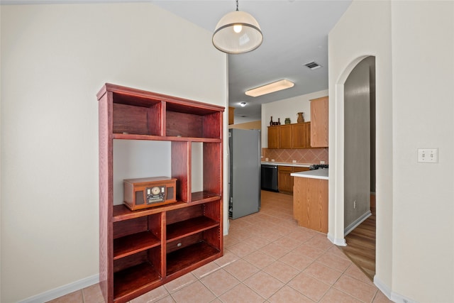 kitchen with pendant lighting, dishwasher, decorative backsplash, stainless steel refrigerator, and light tile patterned floors