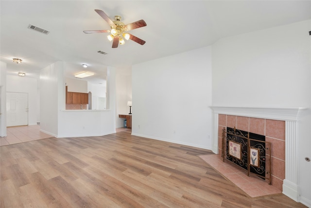 unfurnished living room with a fireplace, ceiling fan, and light hardwood / wood-style floors