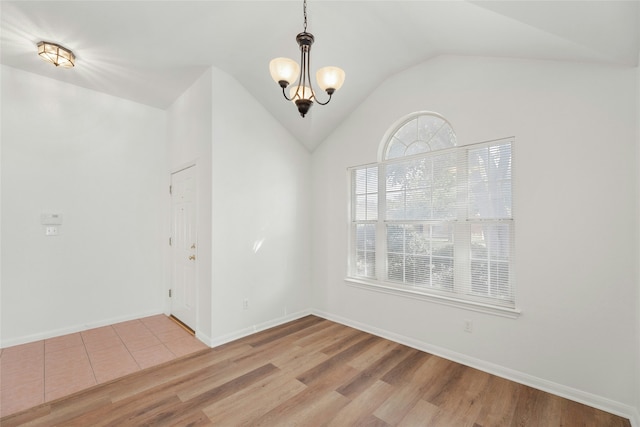 empty room with light wood-type flooring, vaulted ceiling, and an inviting chandelier