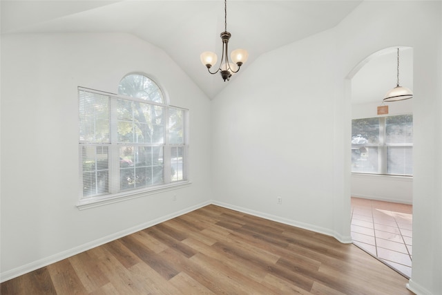 unfurnished room with hardwood / wood-style floors, a chandelier, and vaulted ceiling