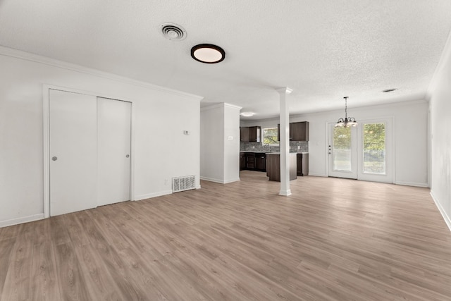 unfurnished living room with ornamental molding, a textured ceiling, and light wood-type flooring