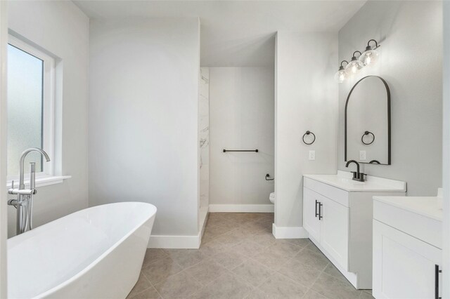 bathroom with a wealth of natural light, a bathtub, vanity, and toilet