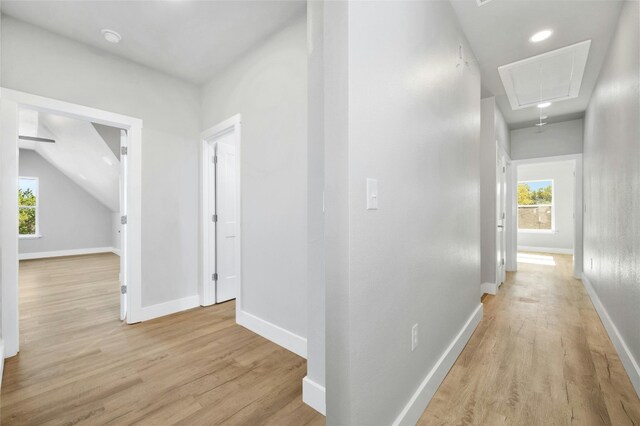 hallway with light wood-type flooring and vaulted ceiling